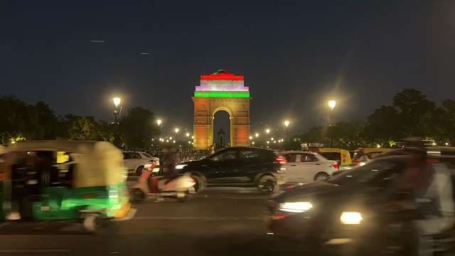 India Gate Illuminated at Night with Bustling Traffic