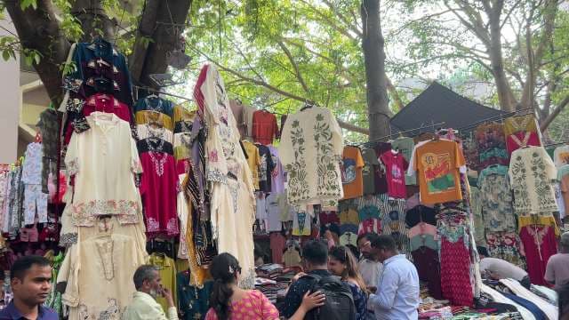 Bustling Outdoor Street Market With Colorful Clothing Stalls
