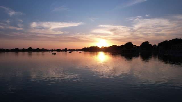 Peaceful Sunset Over Lake With Silhouetted Boaters