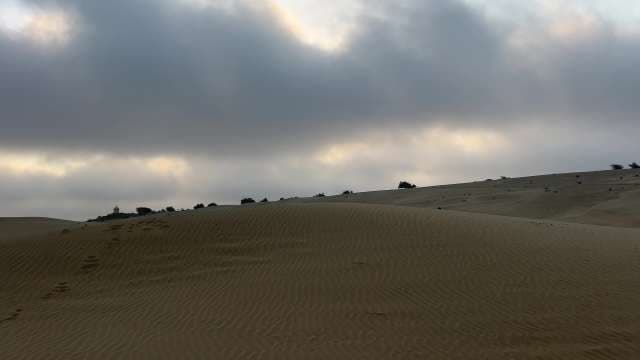 Golden Sand Dunes Under Dramatic Cloudy Sky at Sunrise