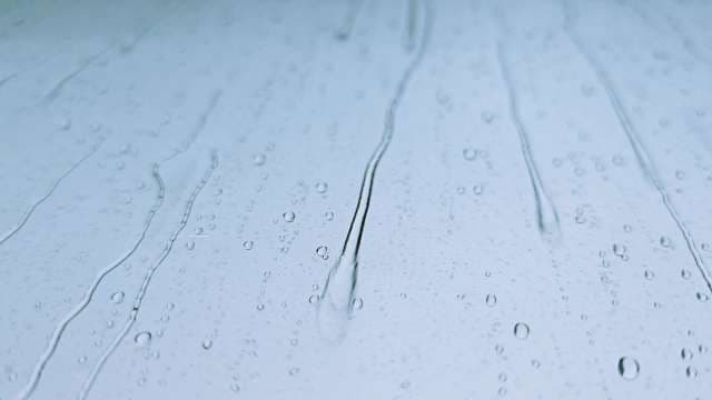 Raindrops Cascading on Glass Window