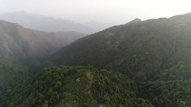 Breathtaking Aerial View of Misty Green Mountains and Remote Village Ridges
