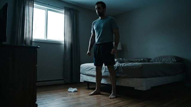 Man Standing Alone in Dark Bedroom Portraying Depression and Isolation