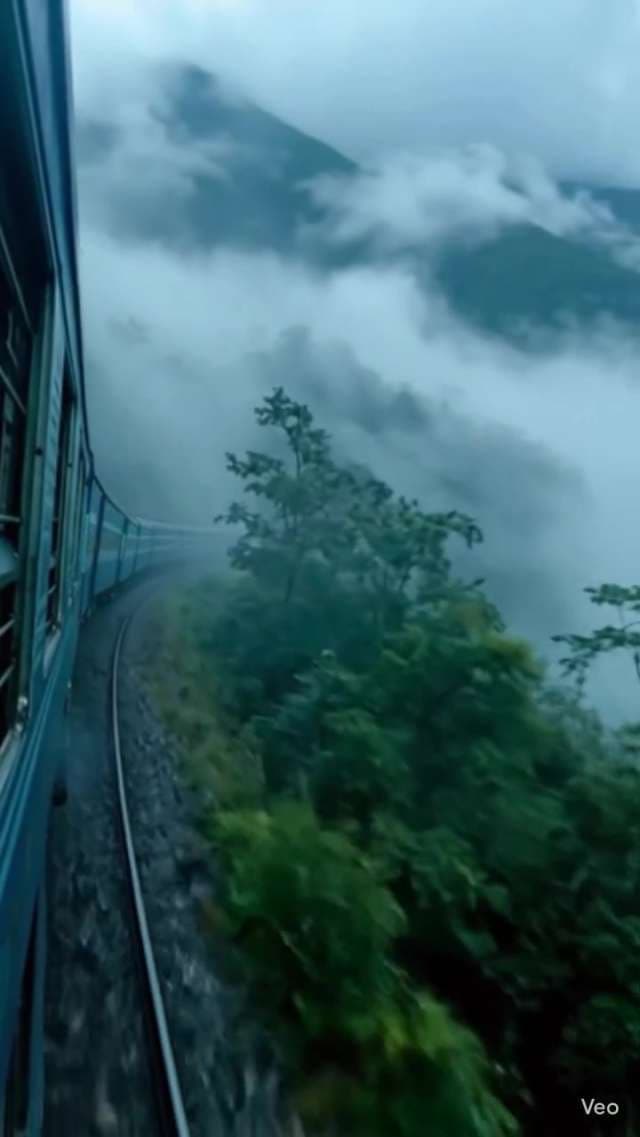Scenic Blue Train Journey Through Foggy Mountain Landscapes