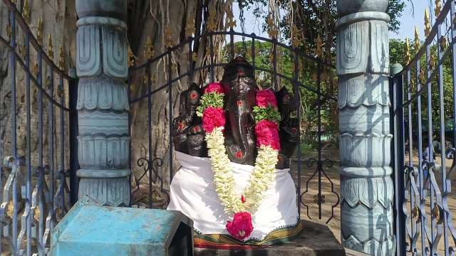 Black Lord Ganesha Statue with Floral Garlands in Outdoor Indian Shrine