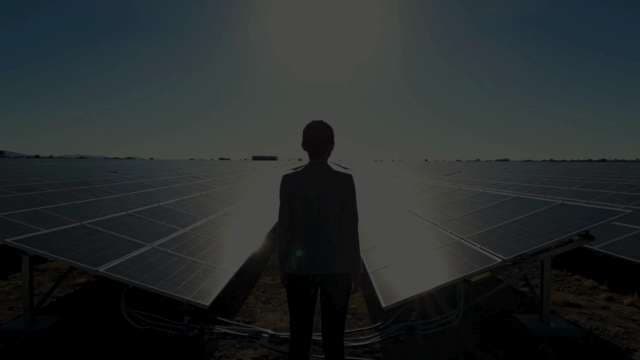 Professional Silhouette at Vast Solar Farm During Sunset