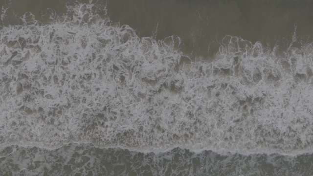 Aerial Top Down View of Crashing Ocean Waves and White Foam
