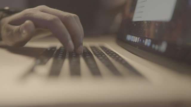 Close-Up of Hands Typing on Laptop Keyboard in Dim Light