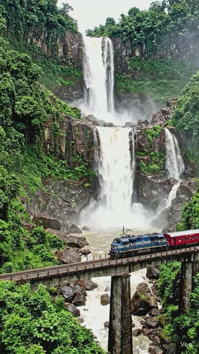Train Crossing Bridge in Front of Massive Tropical Waterfall
