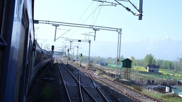 Scenic Train Journey Through Rural Landscape with Snow-Capped Mountains