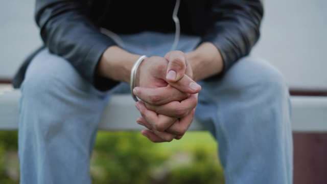 Close-up of Person Sitting with Clasped Hands Outdoors