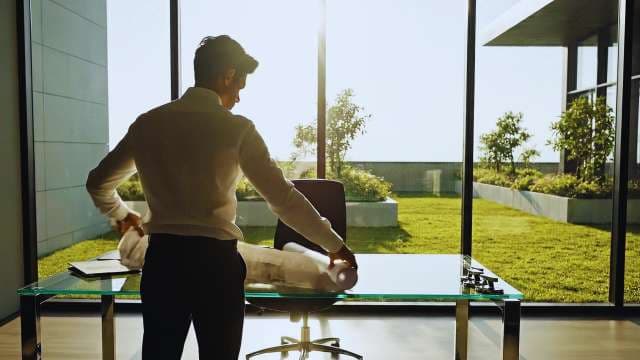 Architect Reviewing Blueprints in Modern Sunny Office