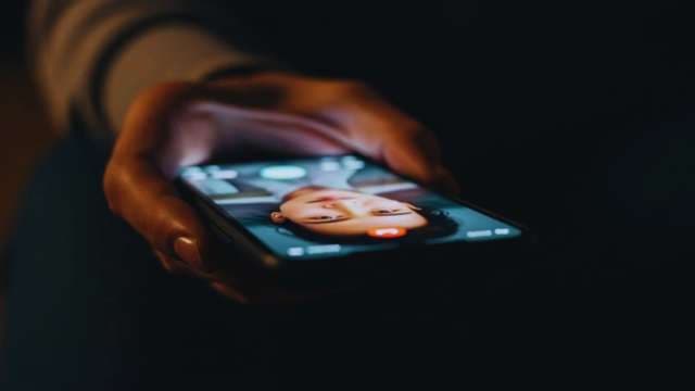 Person Browsing Social Media Profile on Smartphone in Dark Room