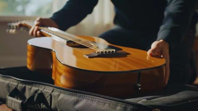 Musician Removing Acoustic Guitar from Padded Gig Bag Case