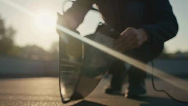 Filmmaker Adjusting Professional Lighting Equipment Outdoors at Golden Hour