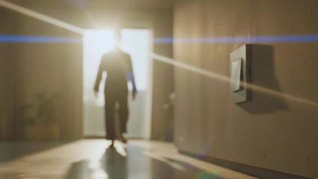 Silhouetted Businessman Walking Towards Bright Sunlight