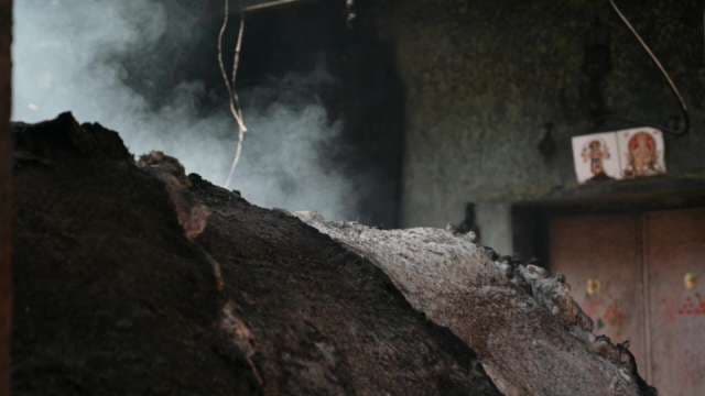 Smoke Rising from Smoldering Material in Dark Industrial Workshop