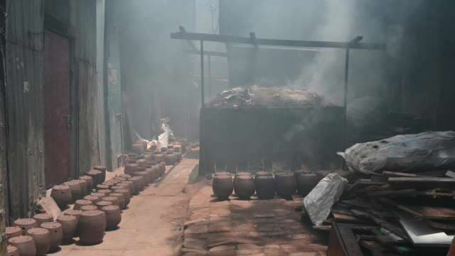 Traditional Clay Pot Firing in Smoking Urban Workshop