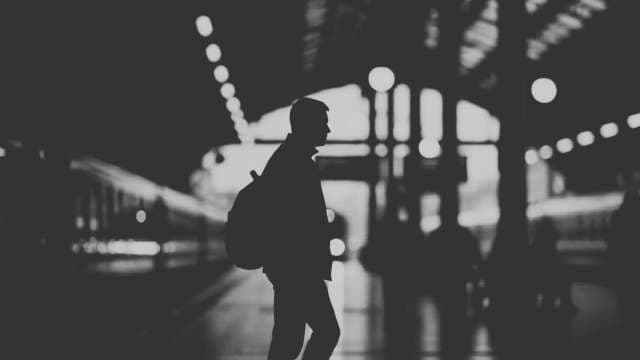 Silhouette of Traveler with Backpack at Night Train Station