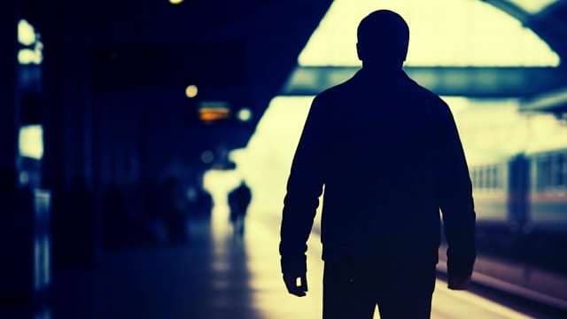 Silhouette of Man Waiting on Train Station Platform at Night