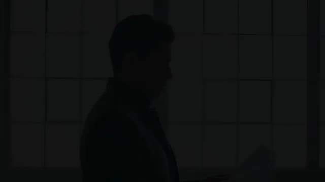 Silhouette of Businessman Reading Documents in Dark Office