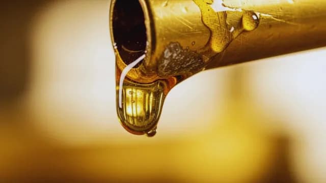 Macro View of Golden Liquid Dripping from a Brass Pipe