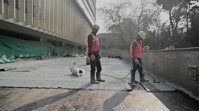 Construction Workers Applying Waterproofing Membrane to Building Roof