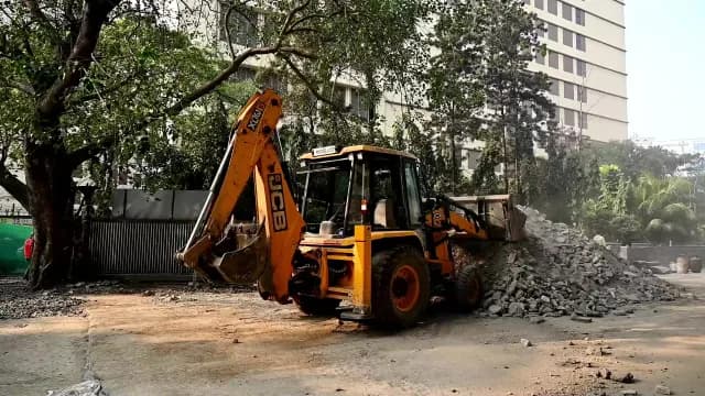 Yellow Backhoe Loader Clearing Debris at Urban Construction Site