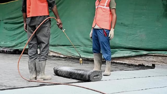 Professional Construction Workers Applying Bituminous Waterproofing Membrane With Gas Torch