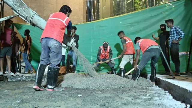 Construction Workers Pouring Wet Concrete at Night on Urban Site