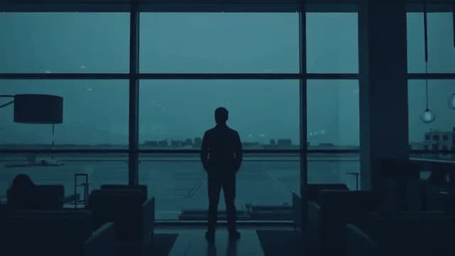 Silhouette of Lone Traveler Watching Airport Runway Through Terminal Window
