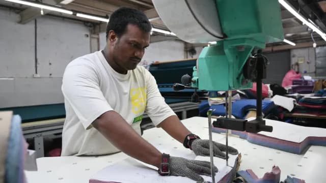 Factory Worker Using Industrial Fabric Cutting Machine in Textile Plant