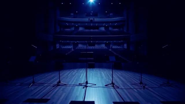 Empty Theater Stage with Microphone Stands Under Blue Spotlight