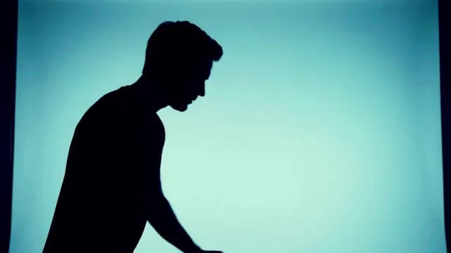 Silhouette Profile of a Man Against Teal Light Background