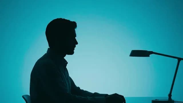 Silhouette of Businessman Working at Desk on Cyan Background