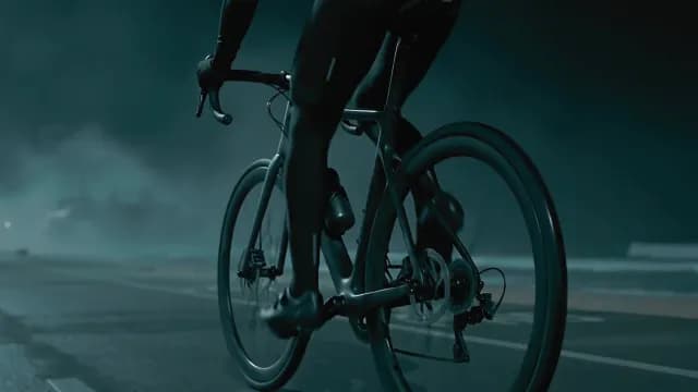 Cyclist riding road bike on foggy night coastal road