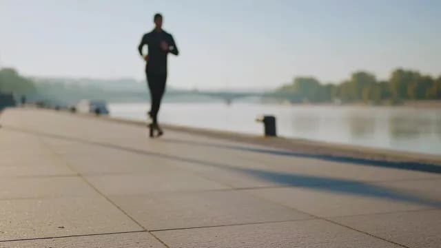 Man Jogging Along Riverfront Promenade at Morning Light