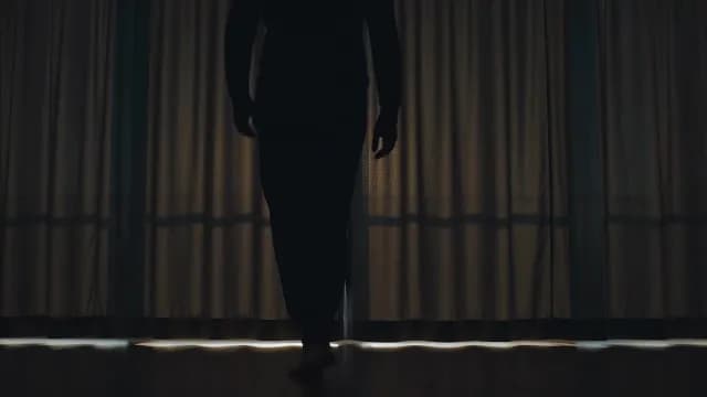 Dramatic Silhouette of Man Opening Curtains of a Dark Room