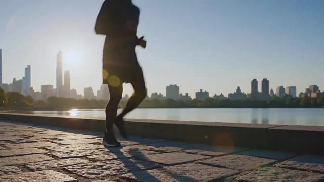 Silhouette of Man Jogging at Sunrise with New York City Skyline
