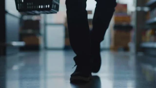 Shopper Walking Through Supermarket Aisle with Hand Basket