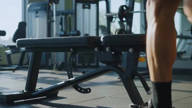 Man Placing Water Bottle Near the Gym Weight Bench in Modern Fitness Center