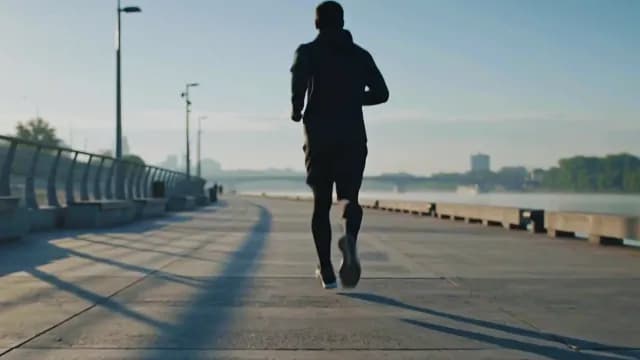 Man Jogging on Riverside Path During Early Morning Sunrise