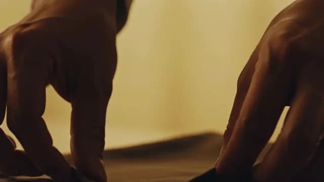 Close-up of Hands Carefully Folding Dark Fabric in Warm Light