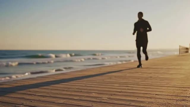 Man Jogging on Coastal Boardwalk at Golden Sunrise