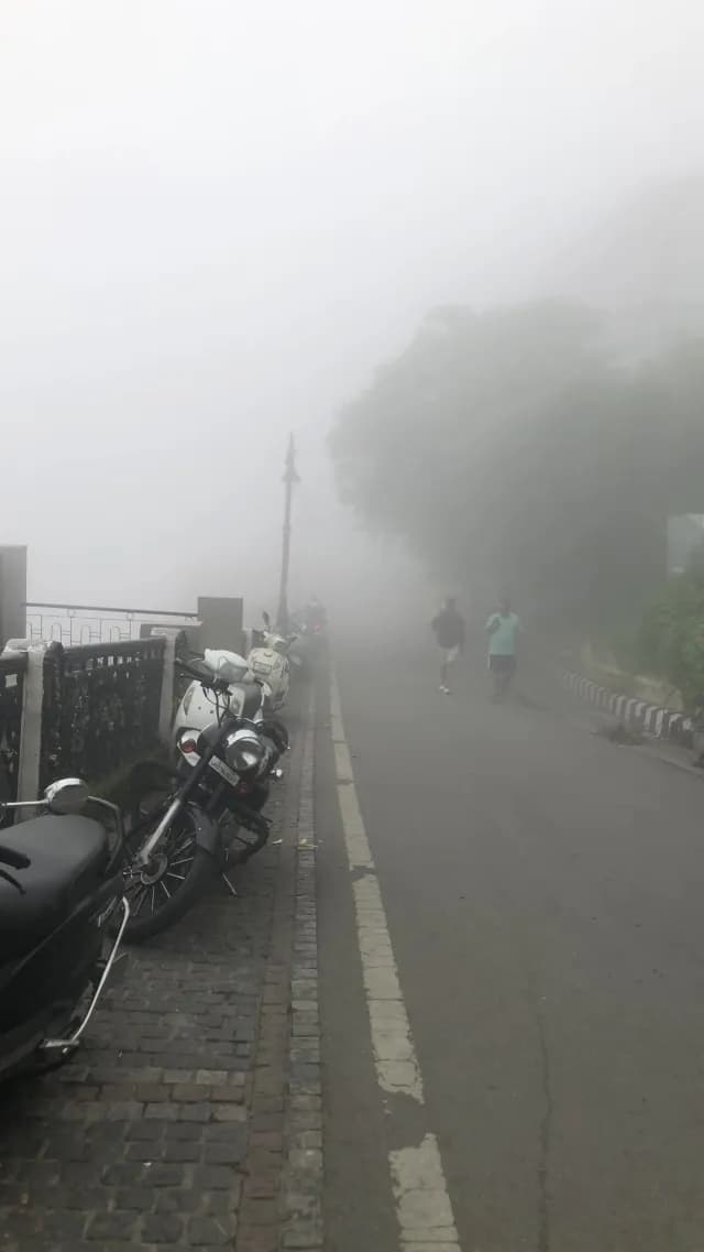 Foggy Hill Station Road with Parked Motorcycles and Pedestrians