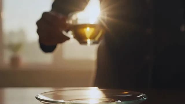 Hand Holding Glass Tea Cup in Golden Hour Sunlight
