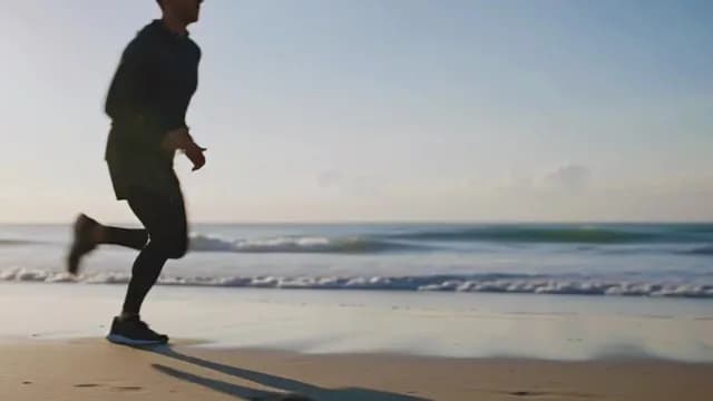 Athletic Man Jogging on Sandy Beach at Sunrise