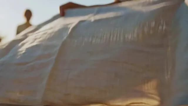 Person Shaking White Linen Sheet Outdoors at Golden Hour