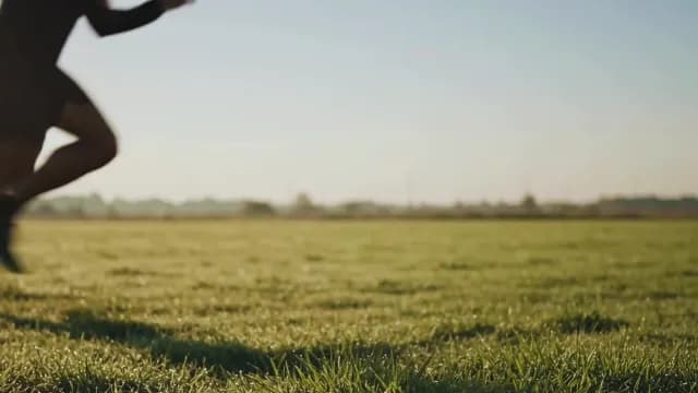 Blurred Athlete Sprinting Across Grassy Meadow at Golden Hour Sunset