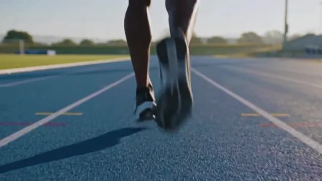 Low Angle Rear View of Athlete Sprinting on Blue Running Track